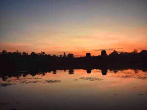 Angkor Wat silhouette reflected in the moat under an orange and pink sunrise sky