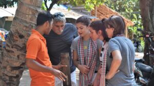 Local guide showing a sugar palm tap to a small group of travellers under a palm tree in a Siem Reap countryside village