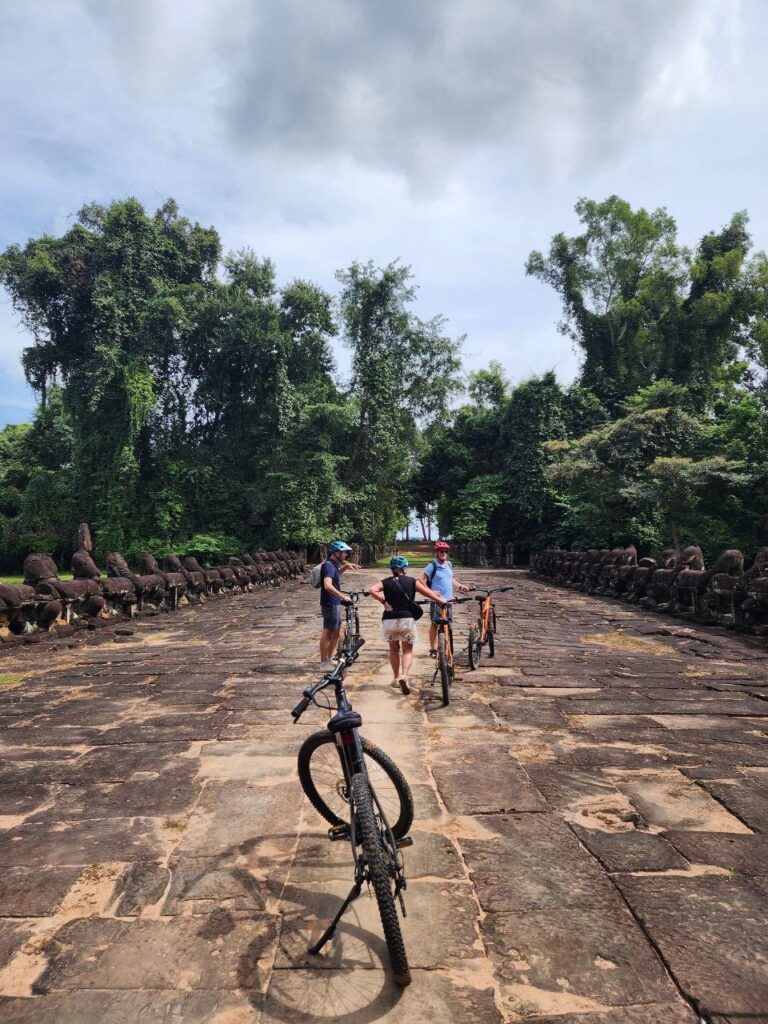 Cyclists arriving Preah Khan from the forest side along the temple causeway.