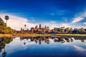 Classic view of Angkor Wat reflected in the lotus pond on the west causeway under a bright blue sky