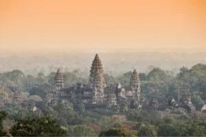 De centrale torens van Angkor Wat rijzen op boven een dichte jungle kroondak in het mistige ochtendlicht, Siem Reap