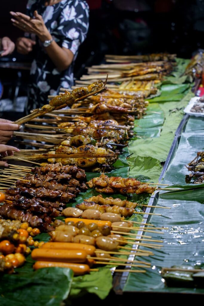 Vendor’s hand picking up grilled frog from the barbecue during a Siem Reap food tour