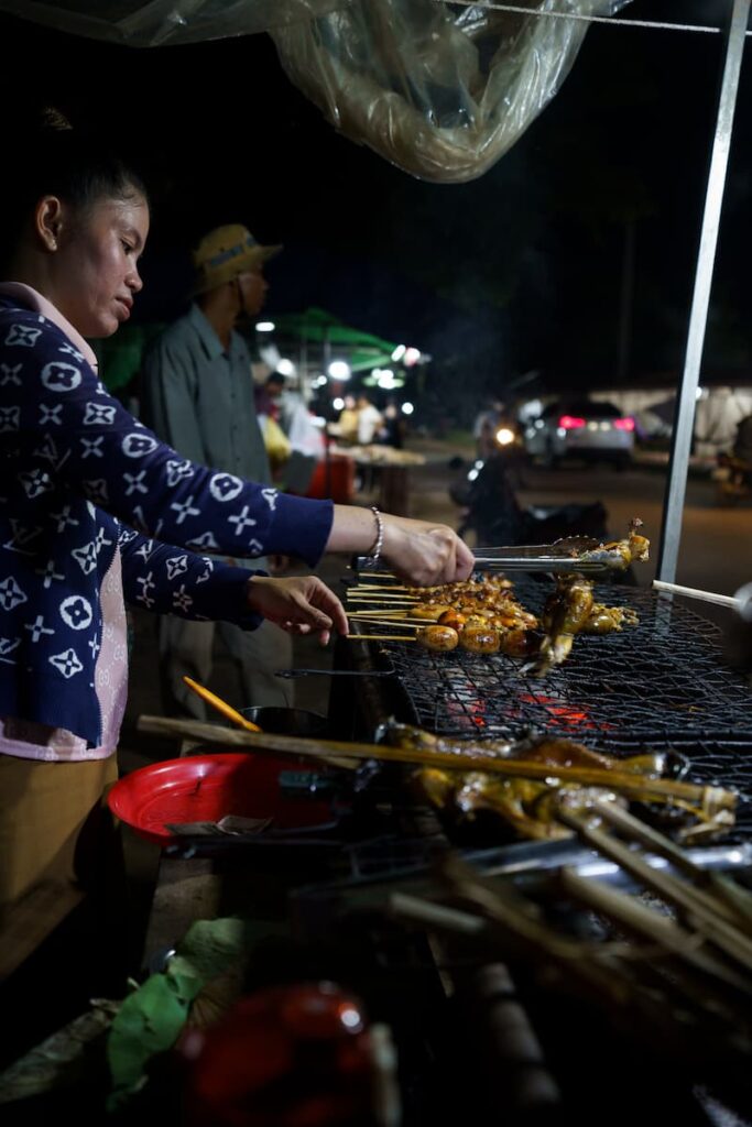 Barbecue vendor picking up skewers from the grill during a Siem Reap food tour