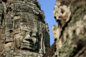 Gros plan d'un visage souriant sculpté en pierre sur une tour du temple de Bayon à Angkor Thom