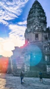 Le temple d'Angkor Wat illuminé par la lumière du lever du soleil tandis que les visiteurs explorent la cour de pierre en contrebas