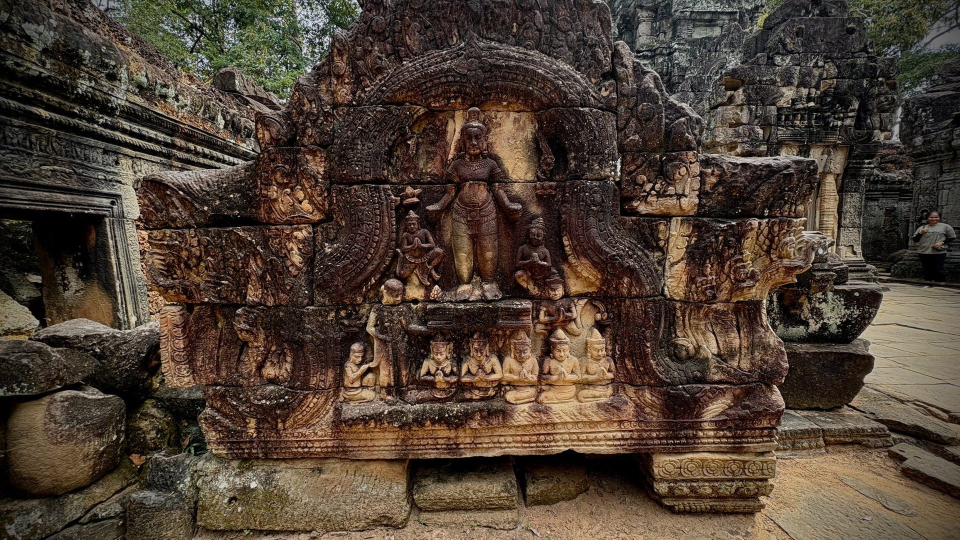 Sandstone bas-relief with carved deity figures on a gallery wall at Angkor