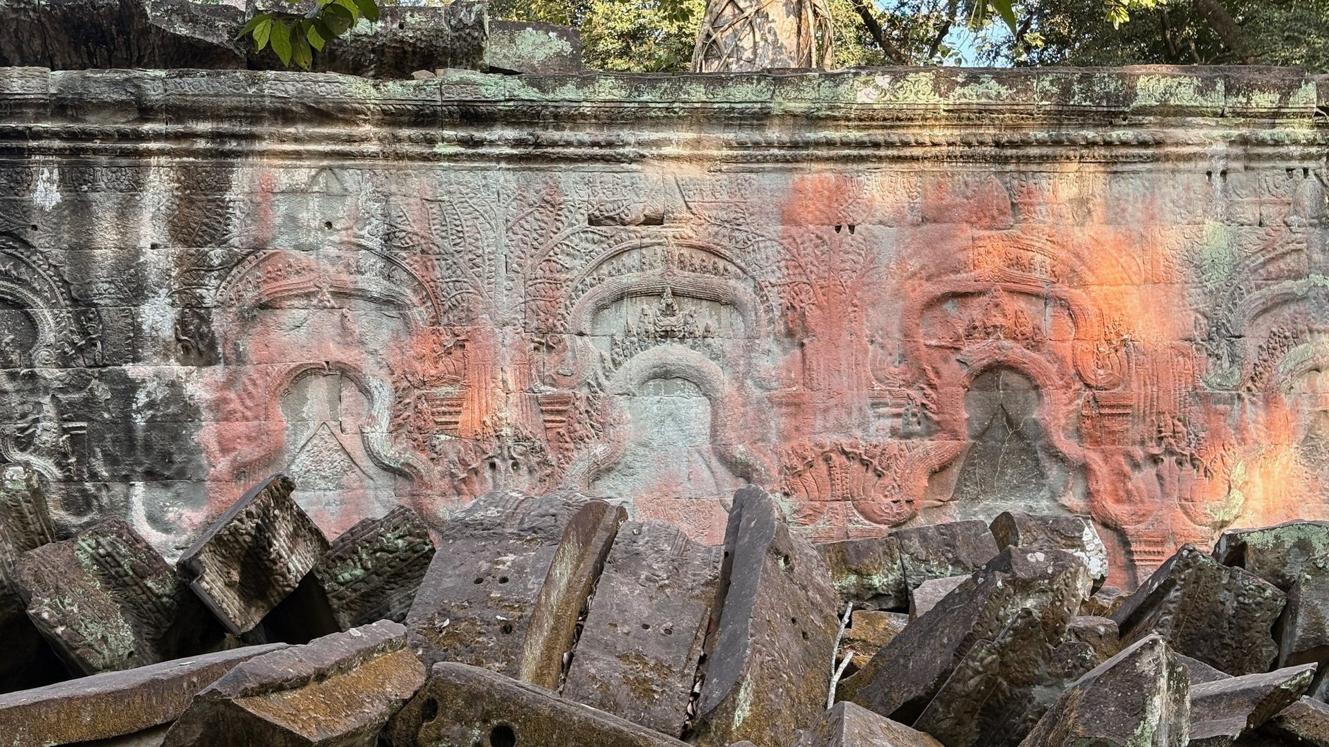 Carved deity faces in shallow relief on an Angkor temple wall
