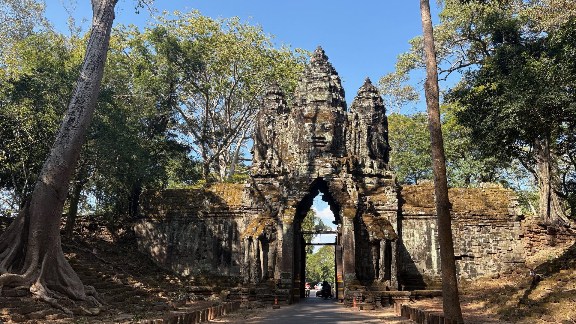 Approach to a carved stone gate flanked by guardian sculptures, Angkor.