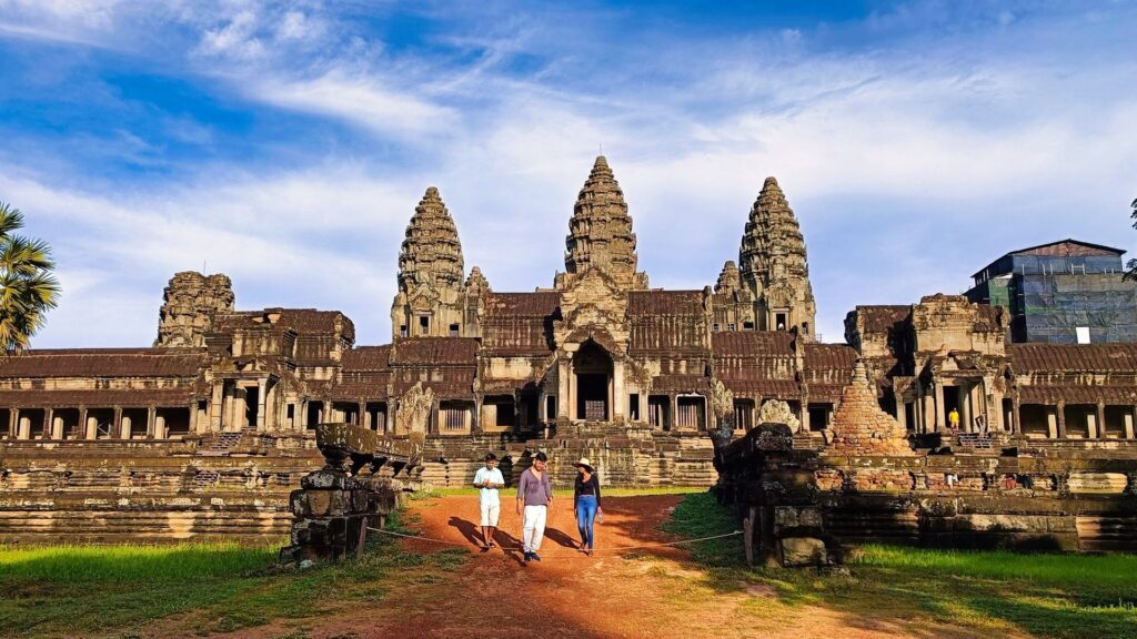Visitors walking toward Angkor Wat under a blue sky