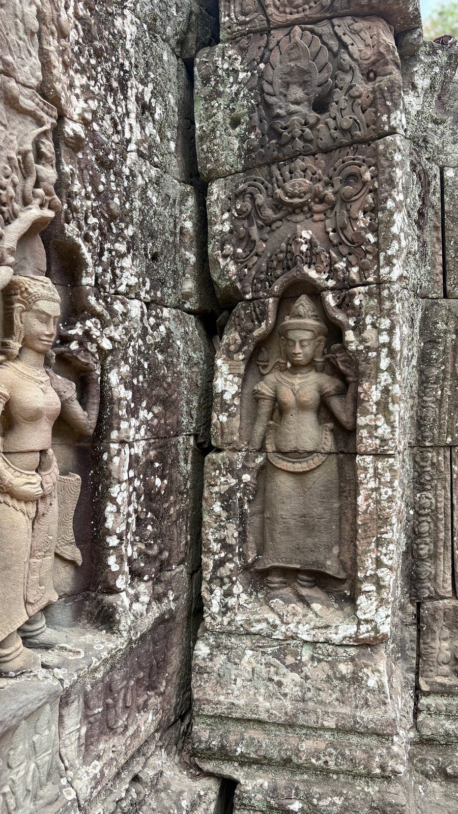 Two carved devata figures in adjacent wall niches at Angkor Wat