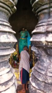 Worshipper in prayer stance before a turquoise Vishnu shrine at Angkor Wat temple complex