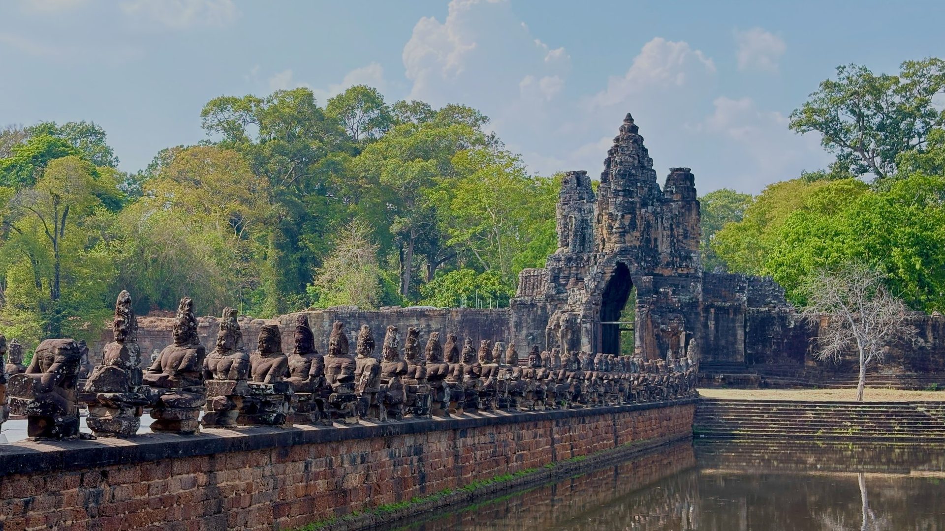 Lange rij van wachterbeelden op een stenen brug bij Angkor Thom.