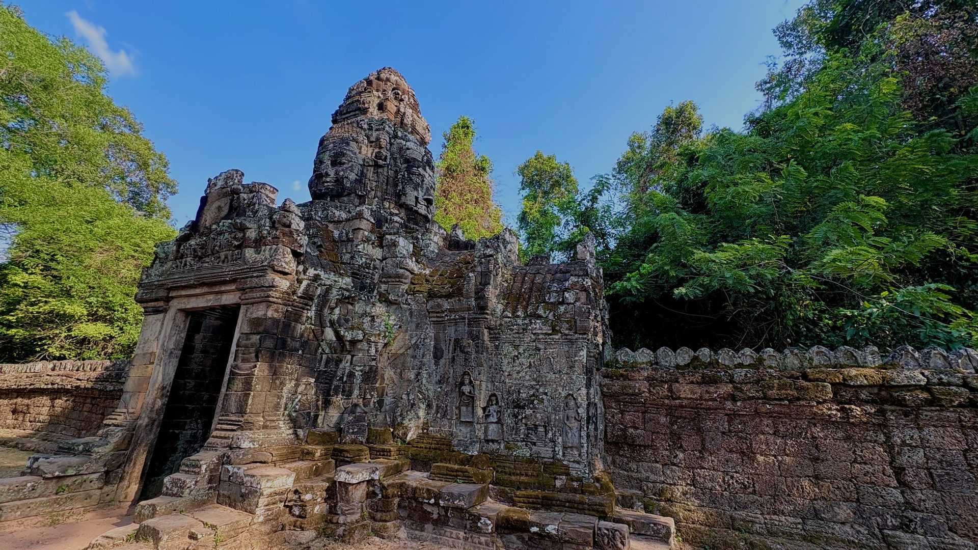 Standing stone tower at Bayon temple under blue sky.