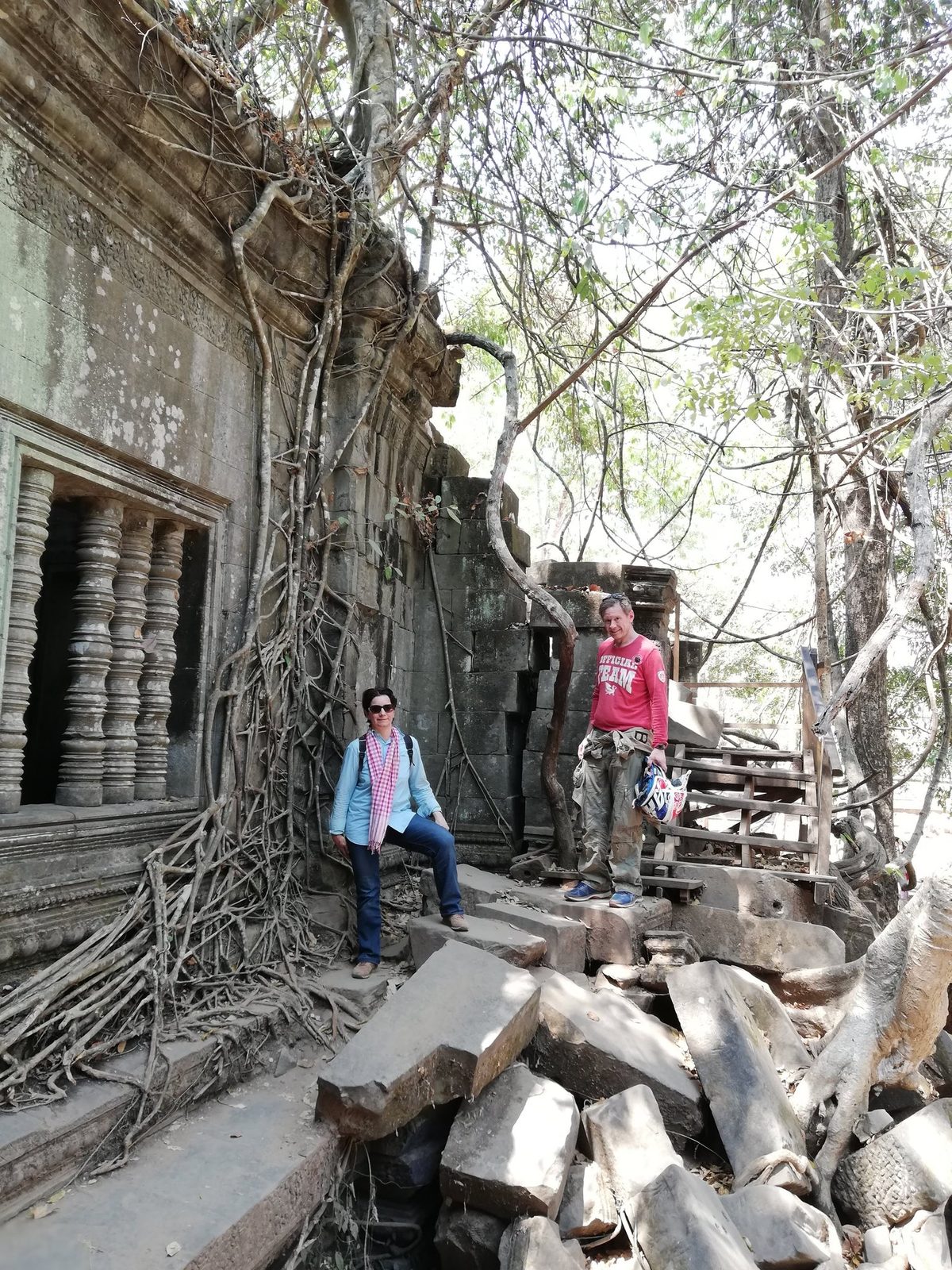 Visitors walk a collapsed gallery overgrown with fig roots at Beng Mealea, covered by the Angkor Pass