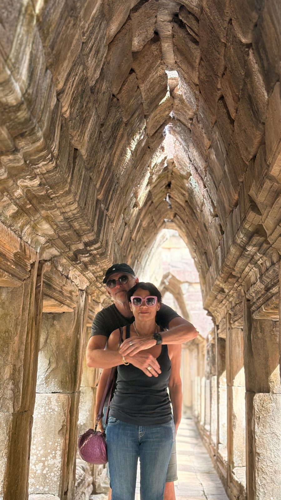 A couple walking a long carved corridor inside an Angkor temple on a private tour