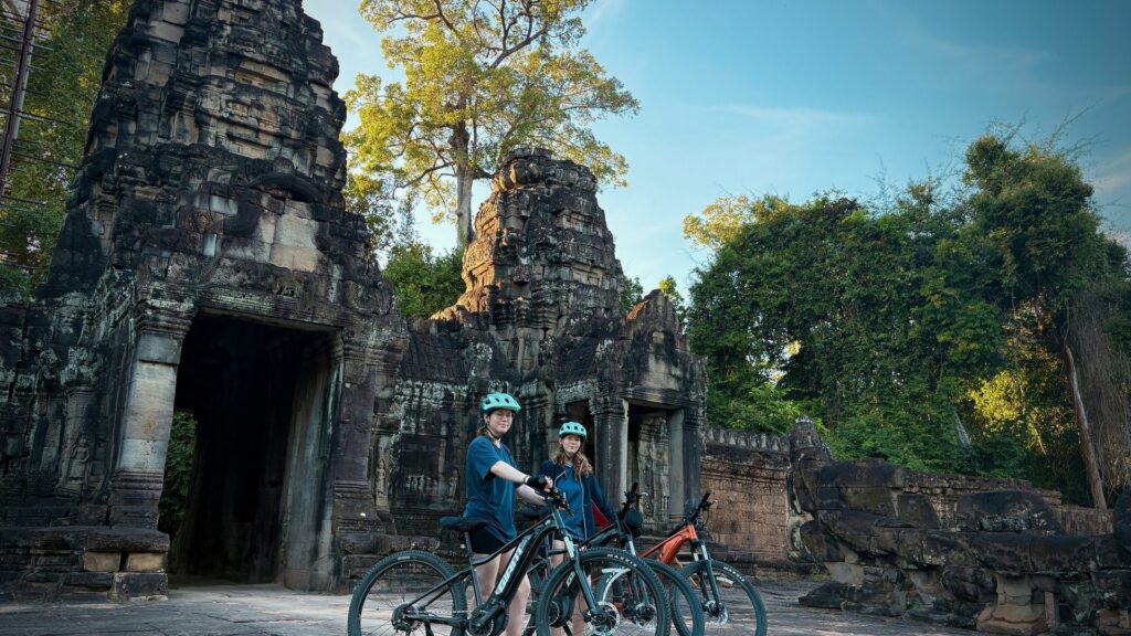 Cycling group pauses at a small Angkor temple gate.