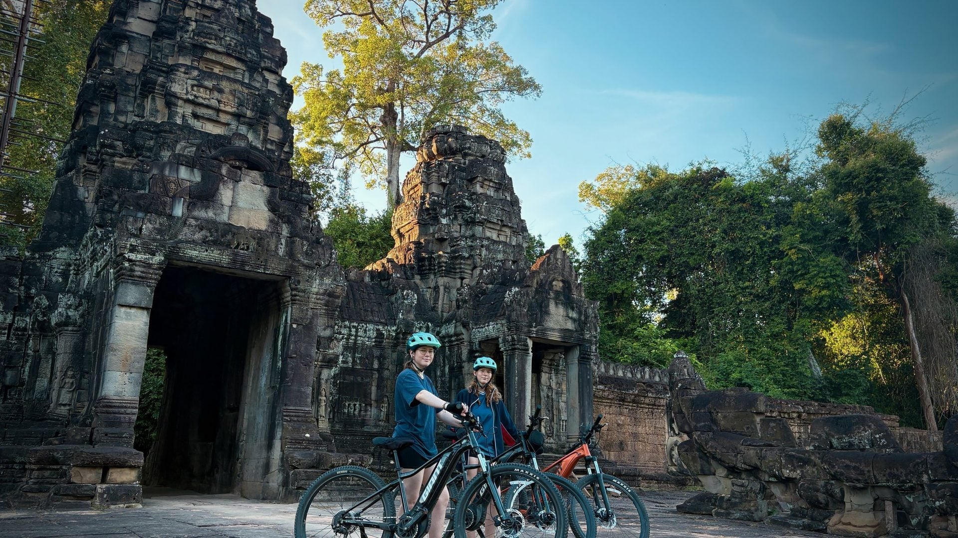 Cycling group pauses at a small Angkor temple gate.