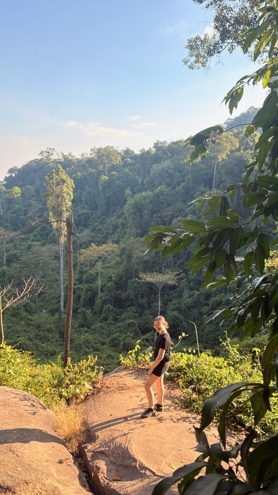 A hiker on a rock viewpoint over the jungle at Phnom Kulen