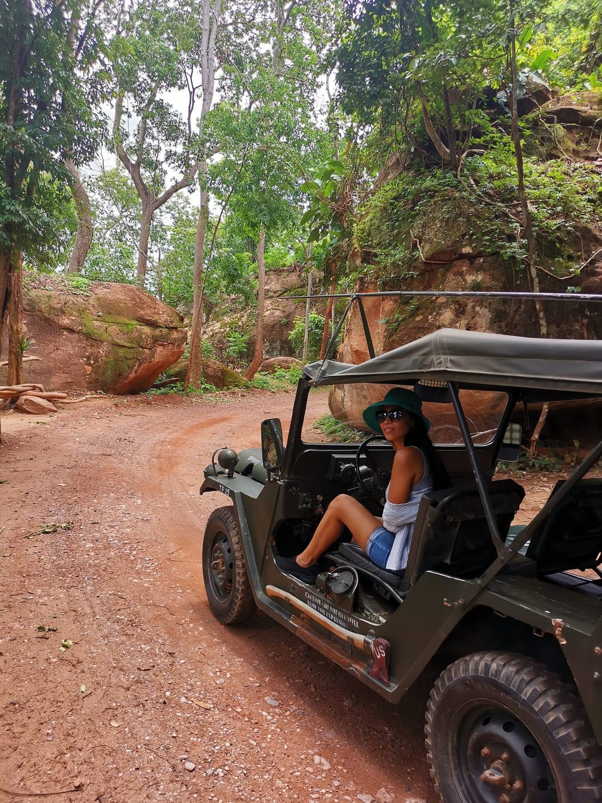 Un visiteur assis dans une jeep vintage garée au bord d'une route forestière