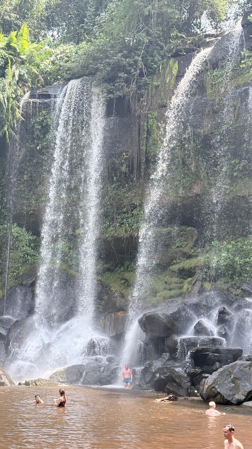 Twin waterfalls at Phnom Kulen National Park with swimmers at the base pool
