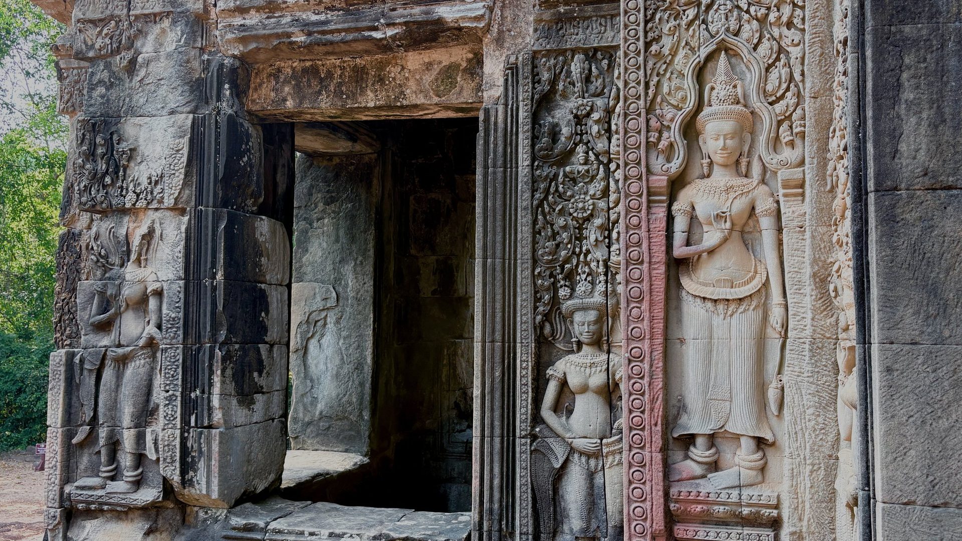 Carved deity reliefs flanking a Thommanon temple doorway.