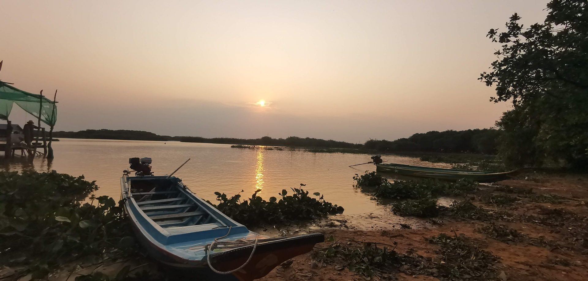 Wooden fishing boat moored at Tonle Sap with golden sunset.