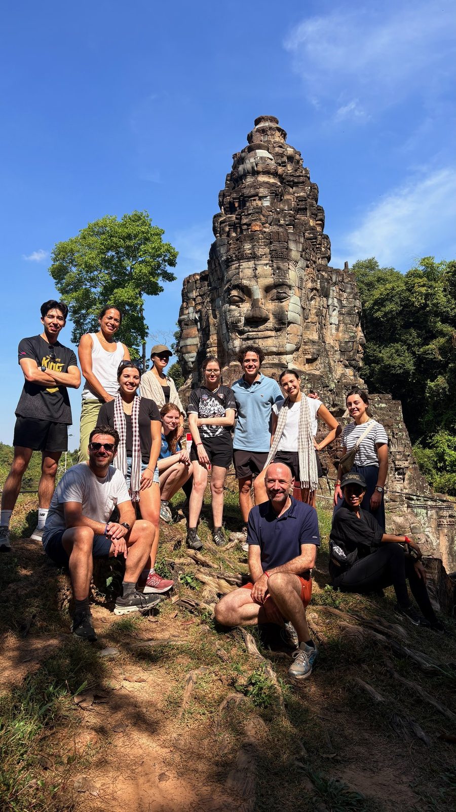 Guests with their Adventures Cambodia guide in front of a Bayon face tower, Angkor