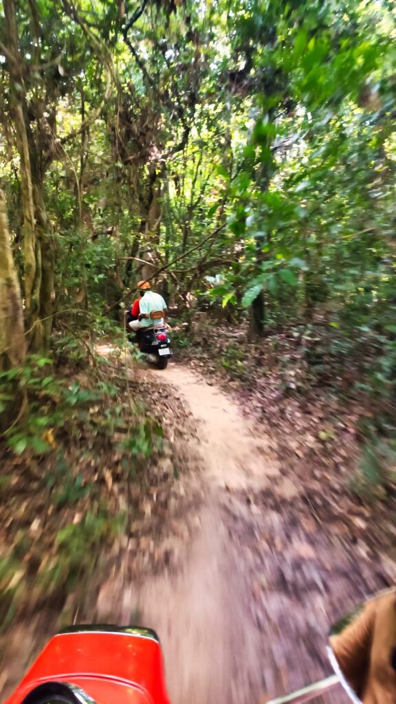 Riding a classic Vespa on a forest trail near Angkor