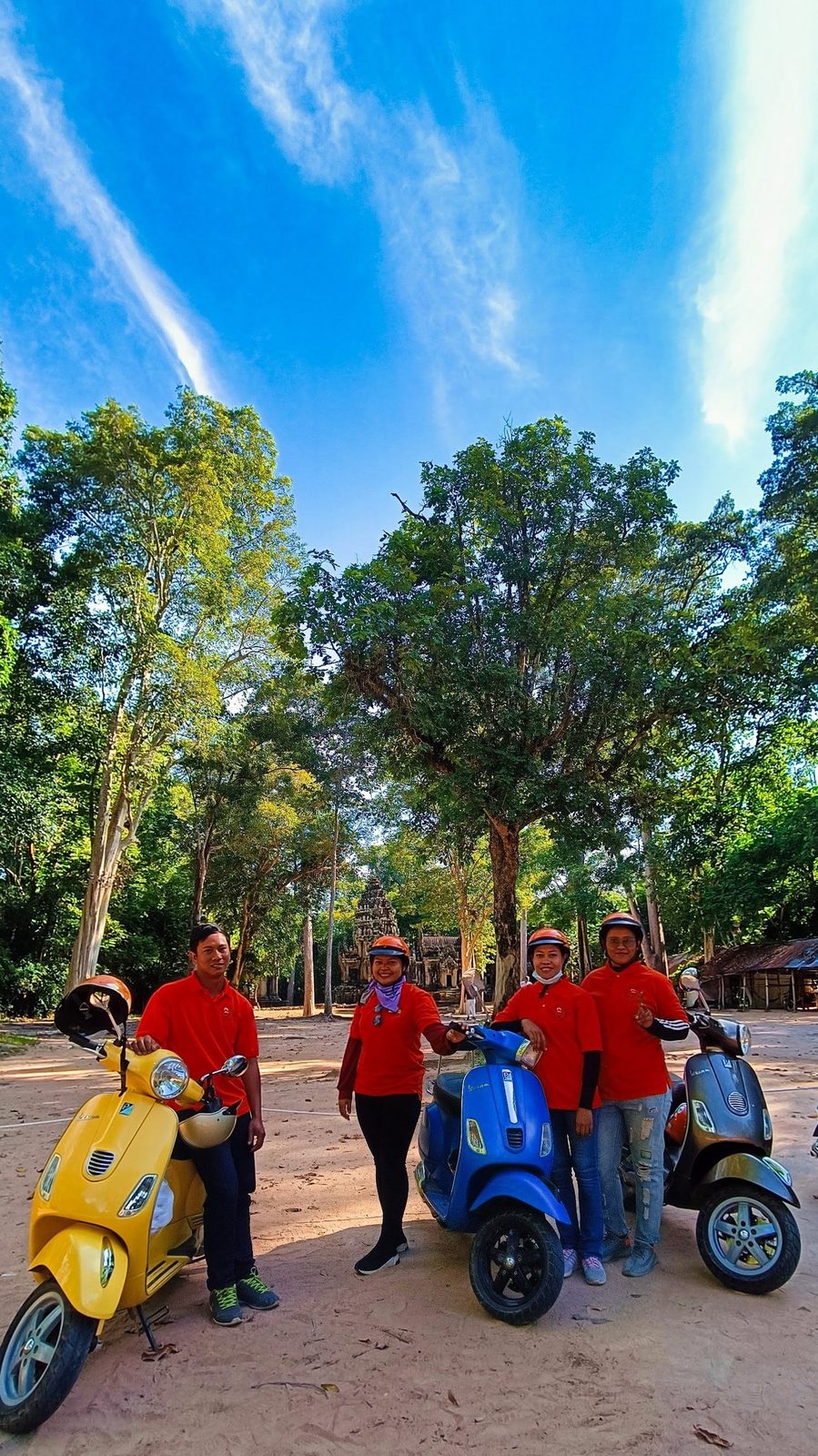 Adventures Cambodia Vespa tour guides on a tree-lined Angkor road
