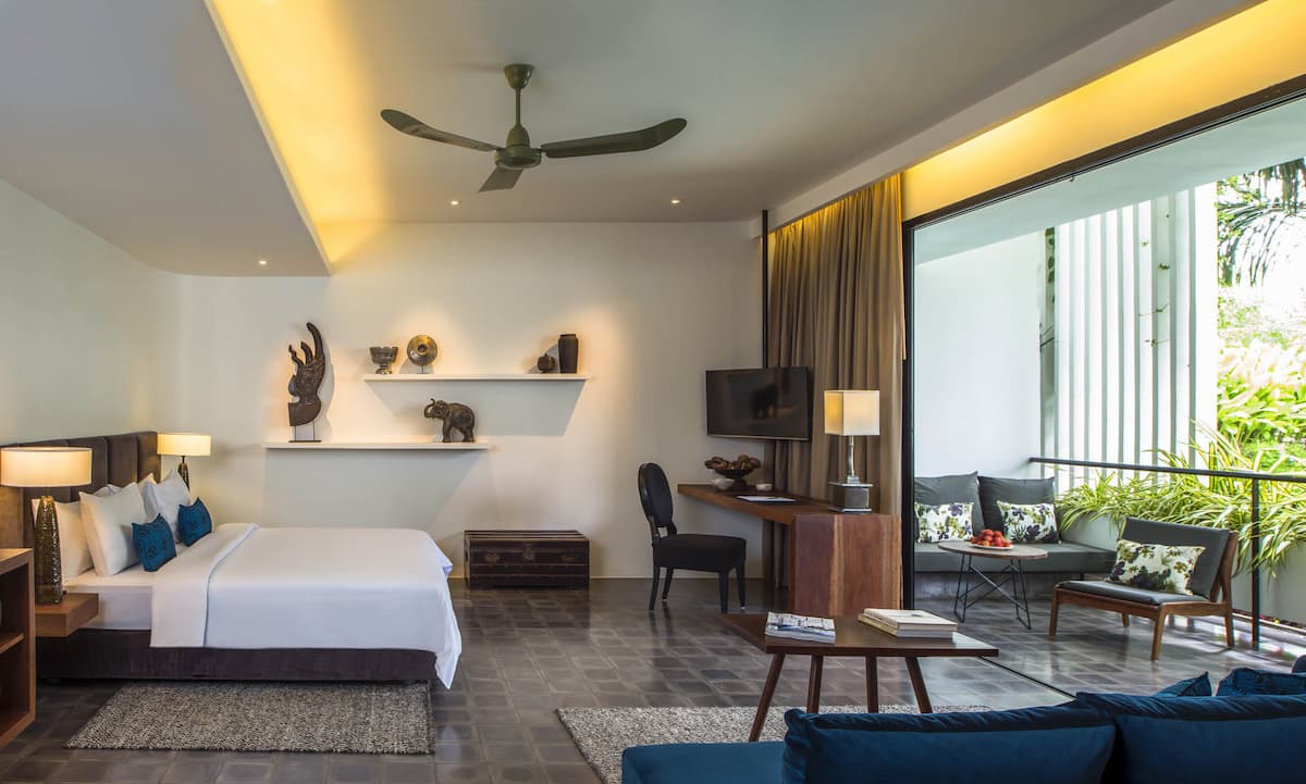 Guest room at Viroth's Hotel Siem Reap with dark tiled floor, artefact shelves and a private balcony seating area