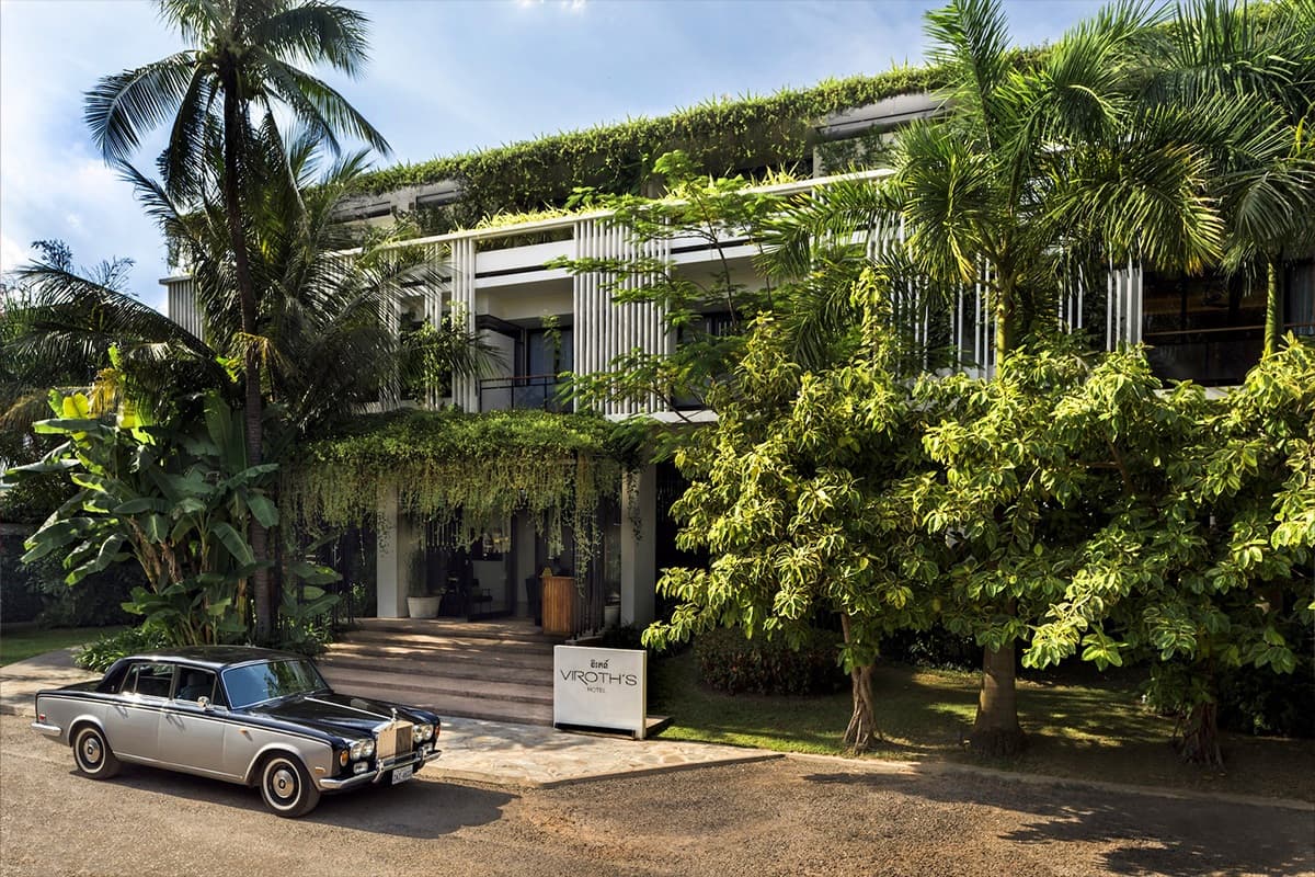 Viroth's Hotel entrance in Siem Reap with vertical gardens on the white facade and a vintage Rolls-Royce parked by the sign