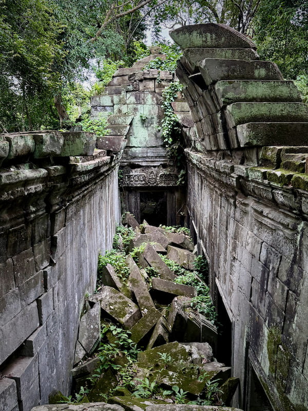 Looking down from the walkway into a collapsed courtyard at Beng Mealea, filled with fallen blocks and new growth