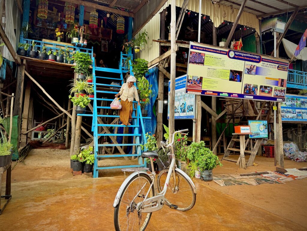 A bicycle parked by the blue staircase of a stilt house in Kampong Phluk