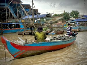 Fisherman in a red and blue wooden boat at Kampong Phluk