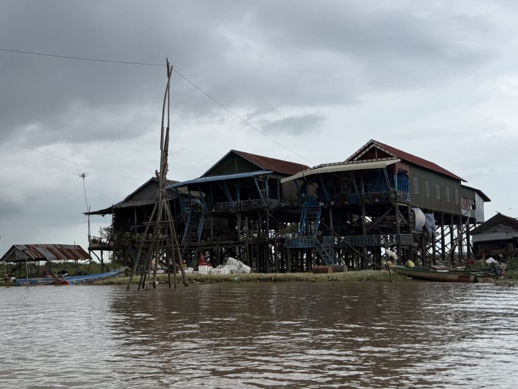 Fishing poles rigged in front of tall stilt houses at Kampong Phluk