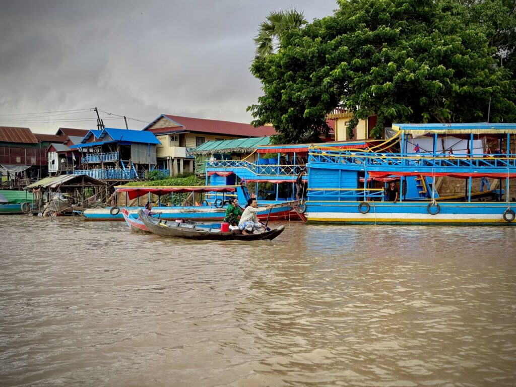 Villagers rowing past the covered tour boats of Kampong Phluk
