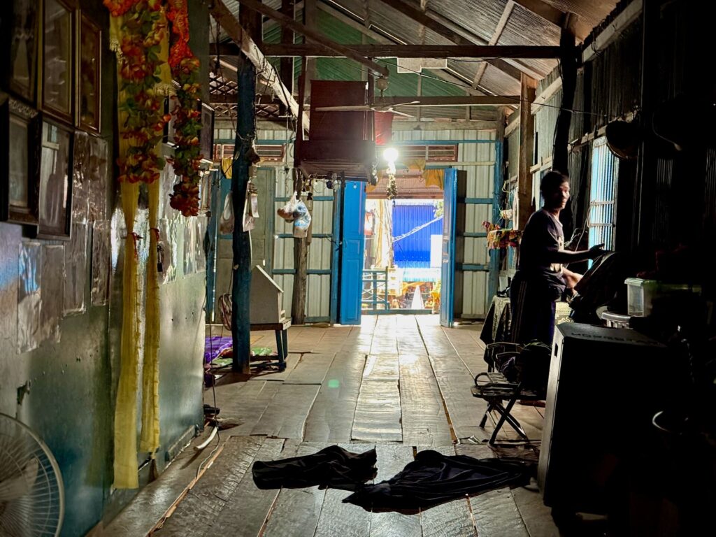 Inside a Kampong Phluk stilt house, looking down the wooden corridor to the bright doorway