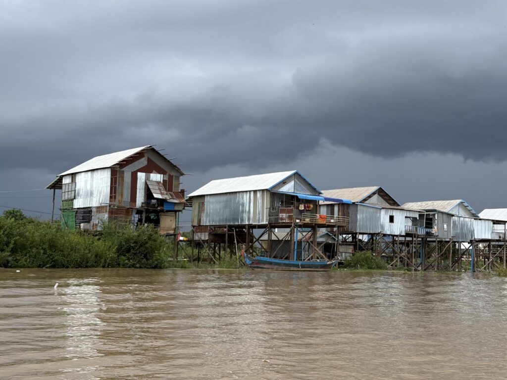Stilt houses of Kampong Phluk standing in high water under a grey sky