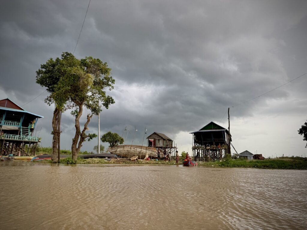Storm light over stilt houses and trees on the Kampong Phluk shoreline