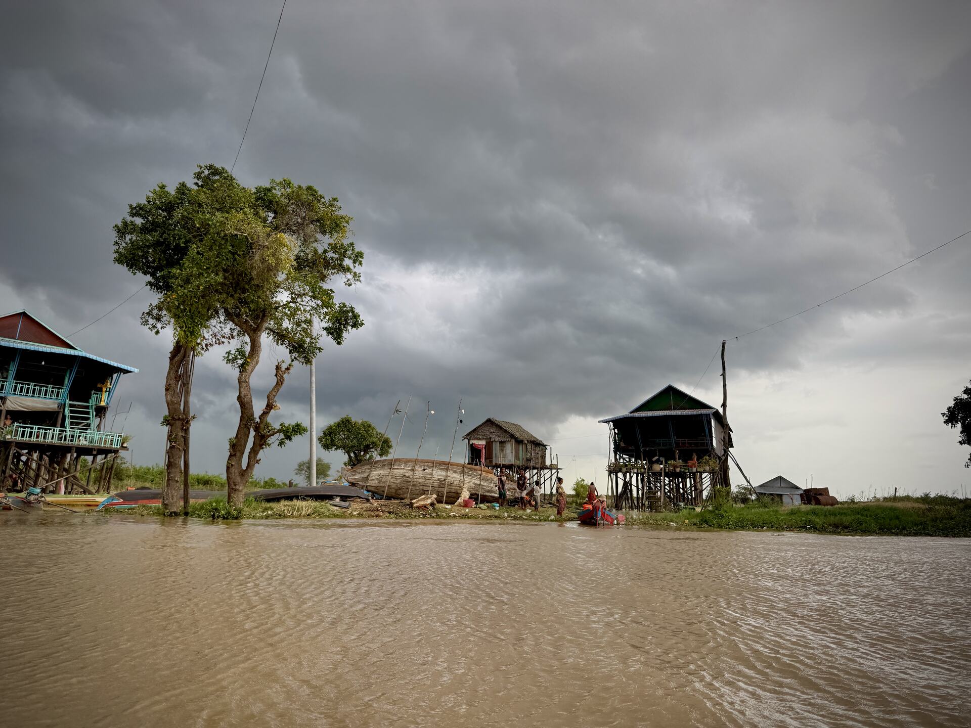 Storm light over stilt houses and trees on the Kampong Phluk shoreline