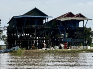 Tall wooden stilt houses with blue staircases above the water at Kampong Phluk