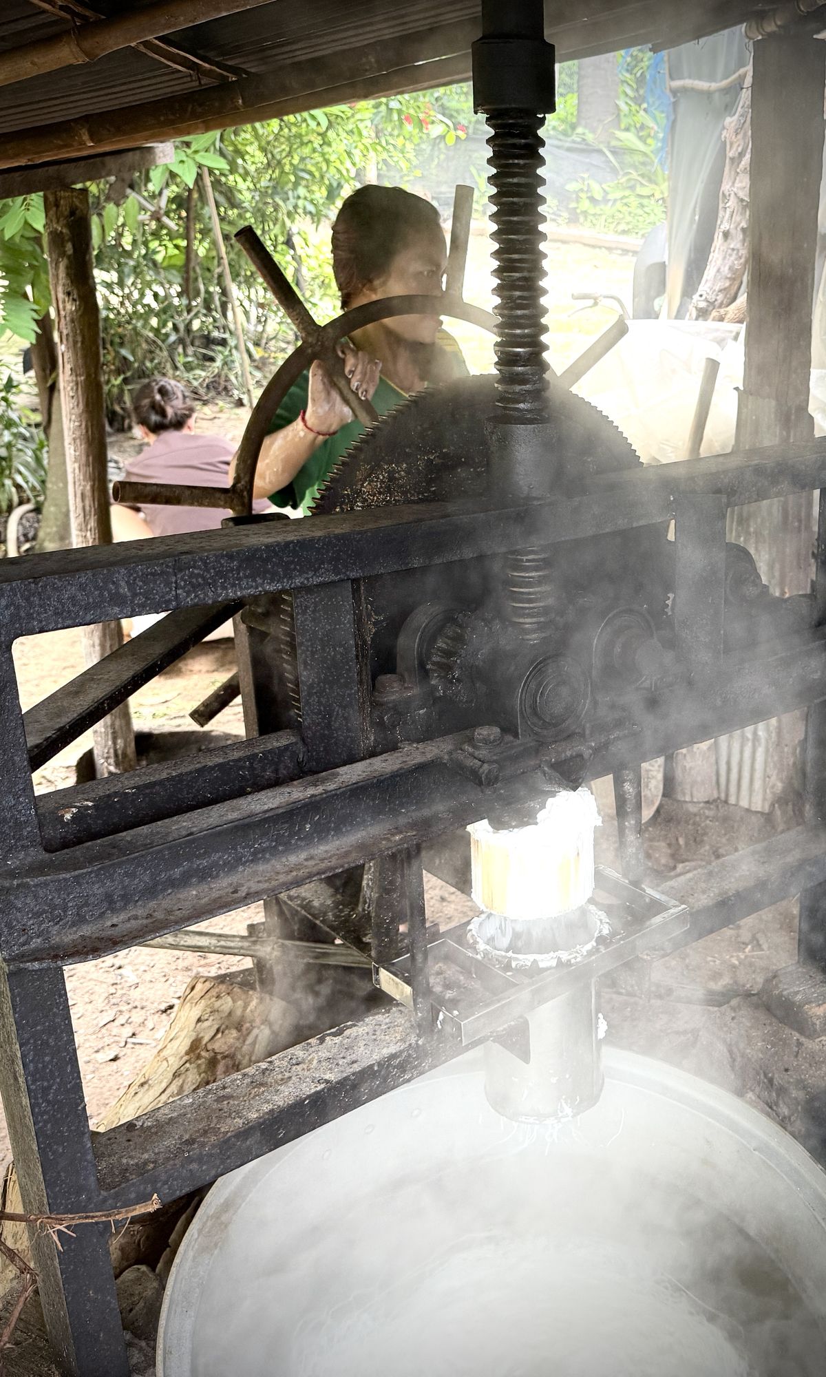 Steam rises around the noodle press as rice dough is forced through the plate