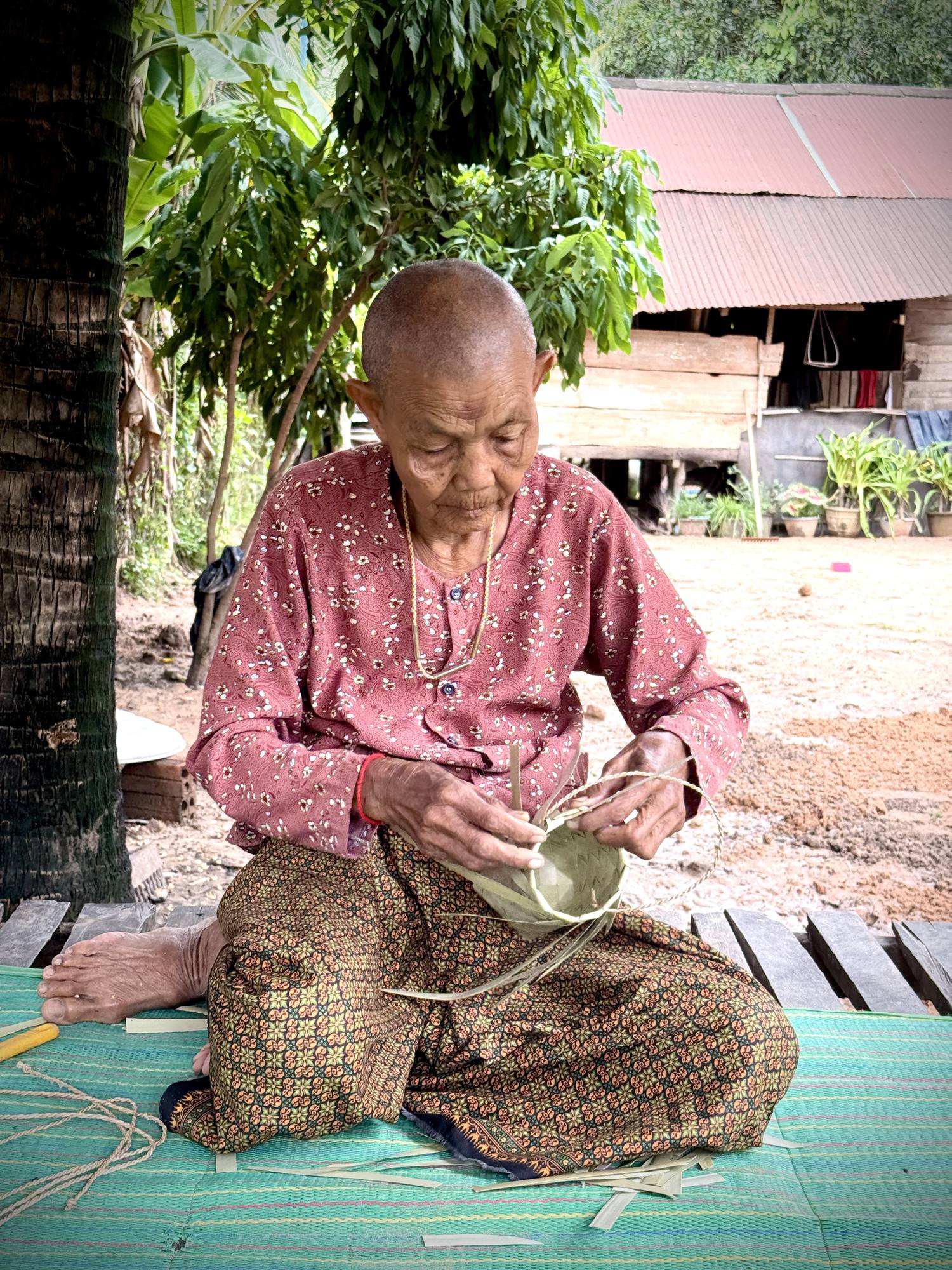 Hands working dried palm strips into shape, the finished pieces beside them