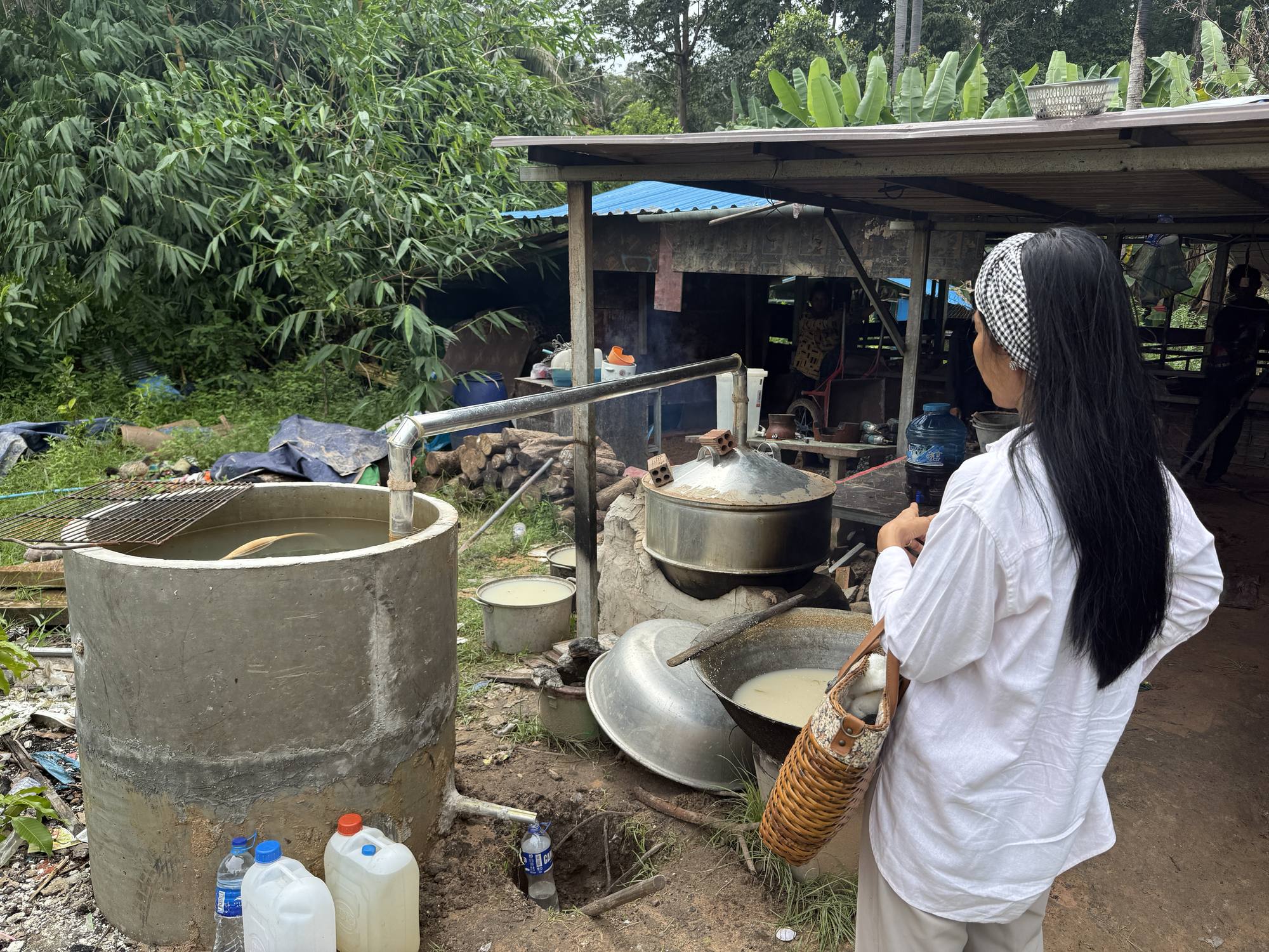 A guest watches the rice wine still at work, the finished spirit collecting in containers