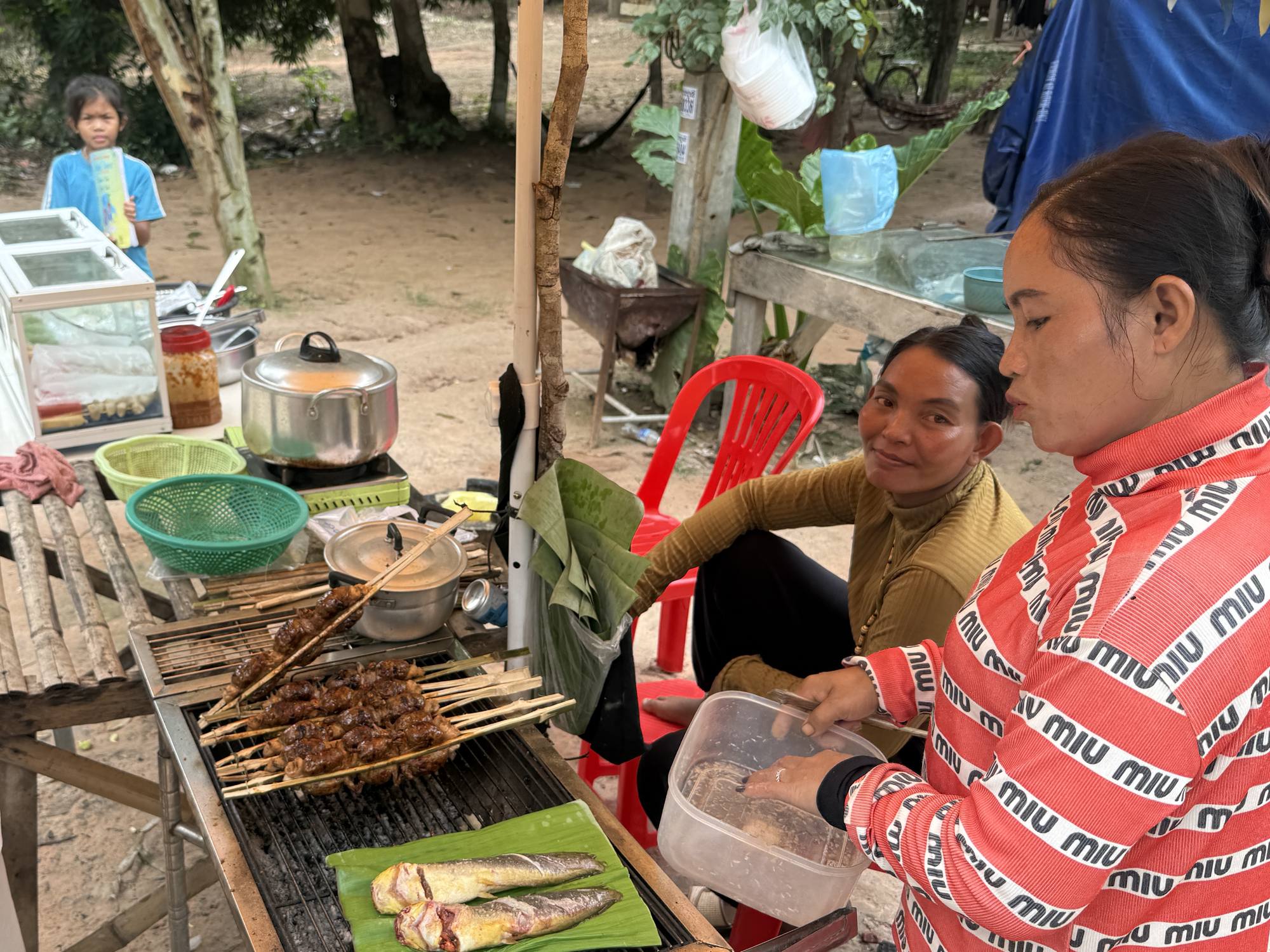 Skewers and a grilled fish on banana leaf at a roadside stall