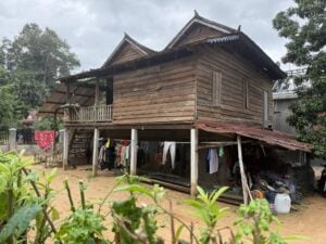 A traditional wooden Khmer house on stilts with laundry drying underneath